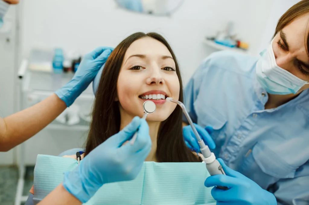Patient smiling as dentist holds a dental mirror and polisher during restorative dentistry treatment in Chicago.