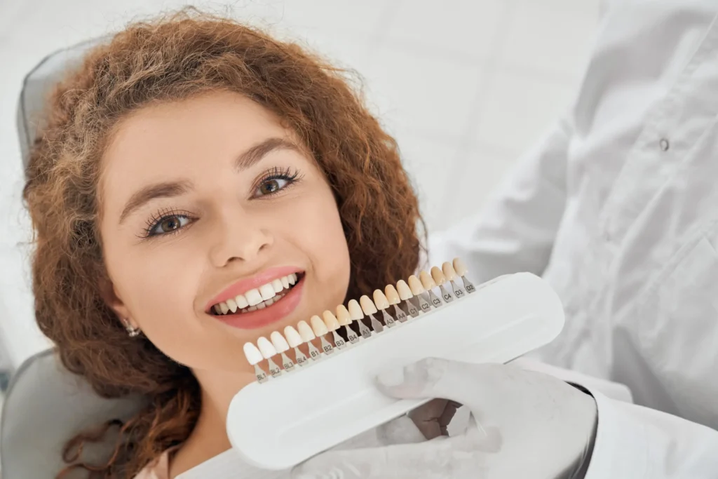 Female patient smiling while dentist holds a shade guide for veneers in Chicago.